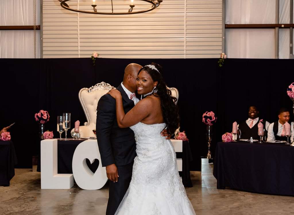 Newlyweds' first dance in front of the LOVE marquee and navy head table