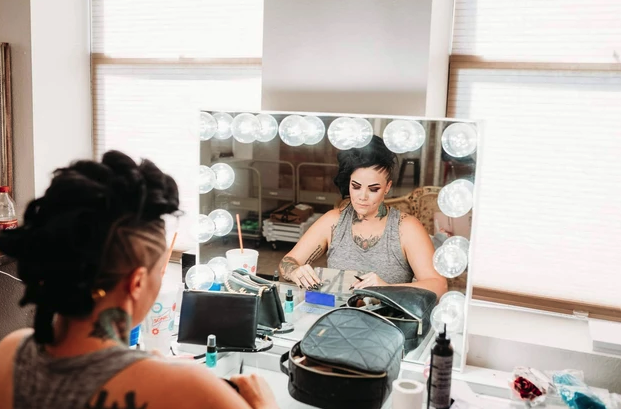 Bride getting ready at the lighted vanity in the bridal suite at Reverie at Diamond D wedding venue