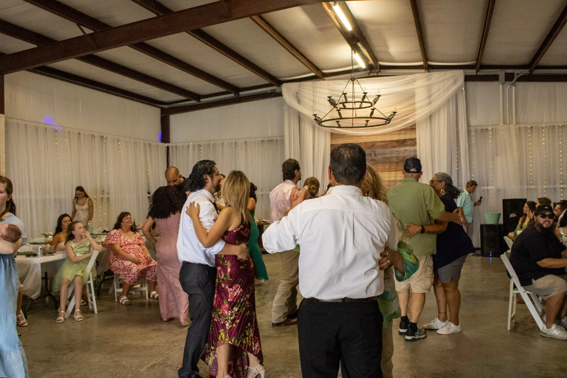 Guests dancing on the reception floor under the chandelier and draped walls at Reverie at Diamond D