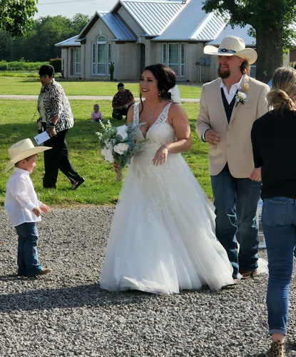 Newlyweds walking the gravel path past the farmhouse at Reverie at Diamond D