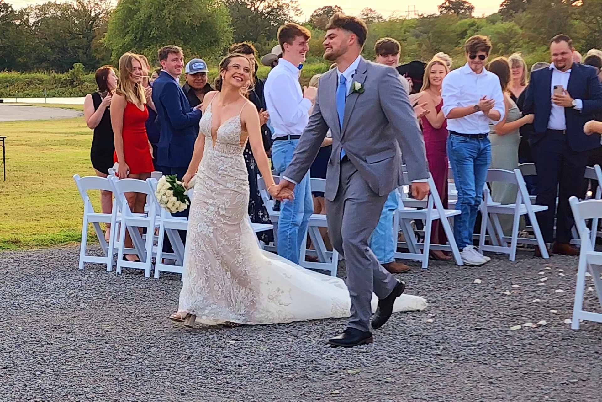 Newlyweds walking the recessional as guests applaud at a Texas lakeside wedding