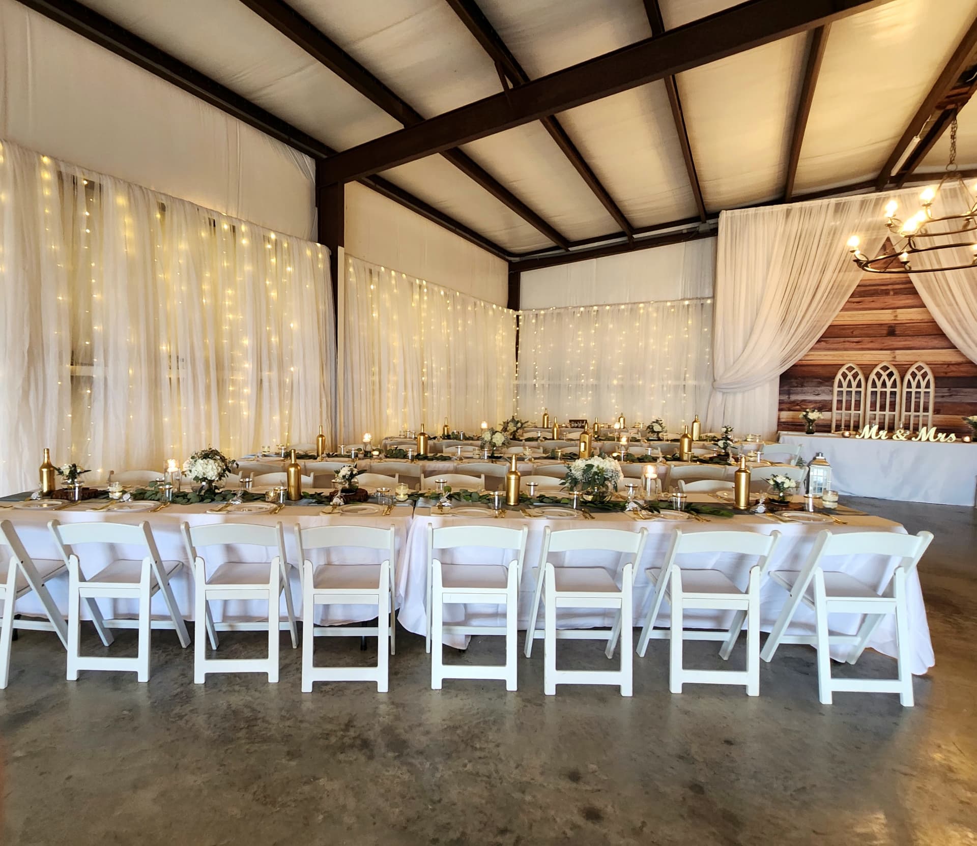Long head tables with gold accents set inside the barn at Reverie at Diamond D in Normangee, TX