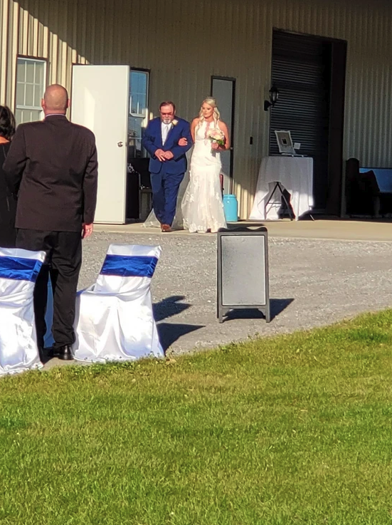 Bride escorted down the aisle toward the lakeside ceremony at Reverie at Diamond D