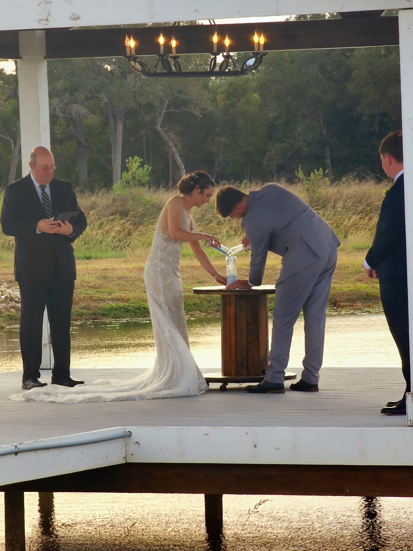 Couple performing a unity sand ceremony on a spool table over the lake