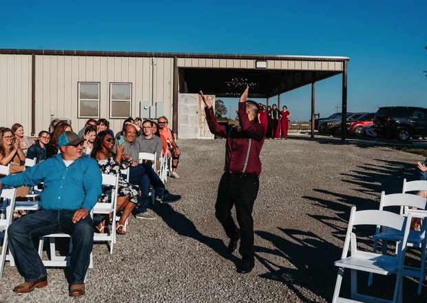 Groom celebrating with raised hands as guests cheer along the outdoor aisle