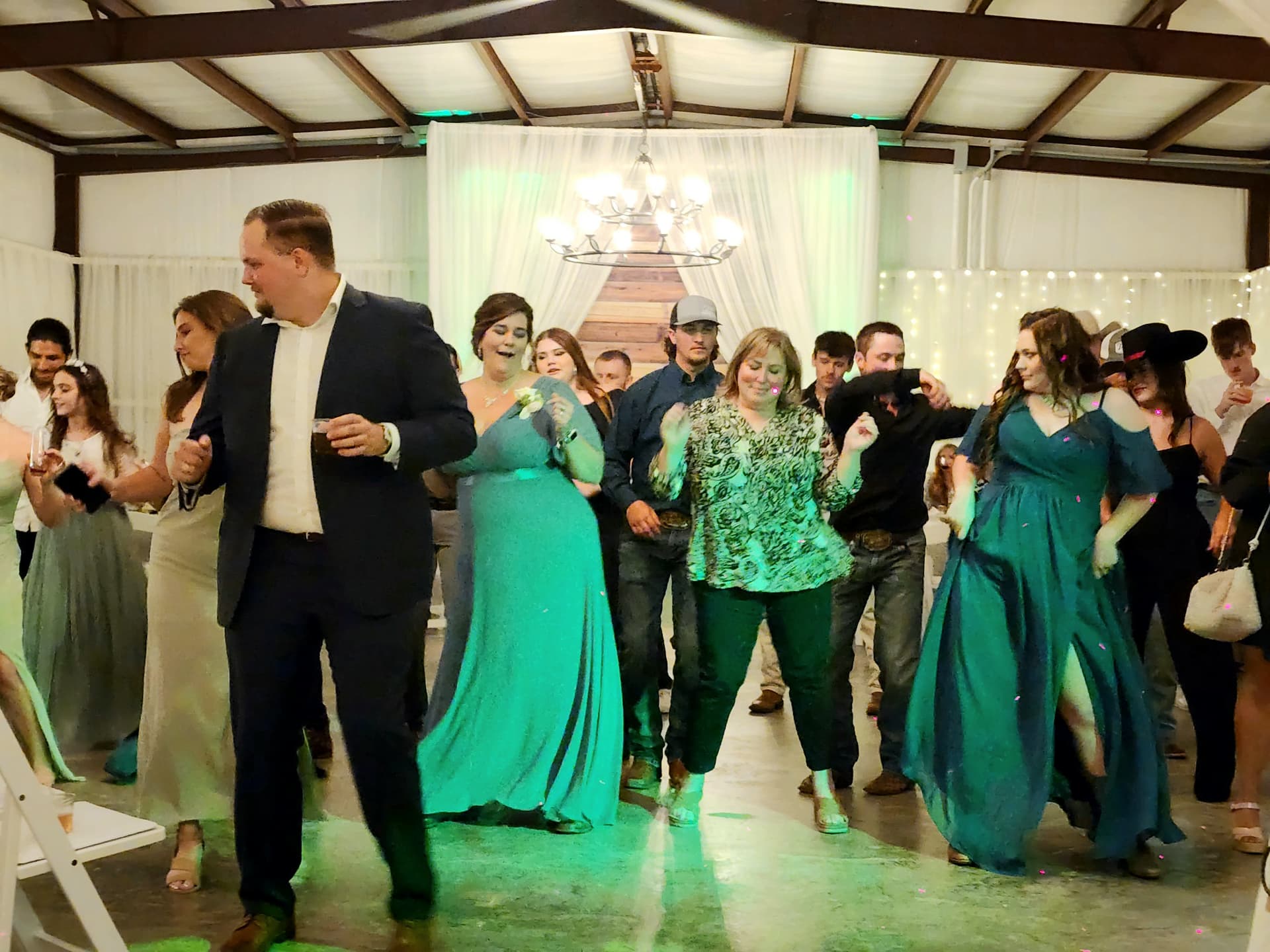 Guests filling the barn dance floor under the chandelier at a Reverie at Diamond D reception