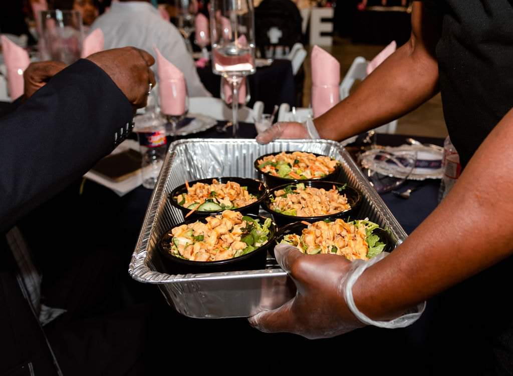 Catering staff serving plated salads to guests at the reception