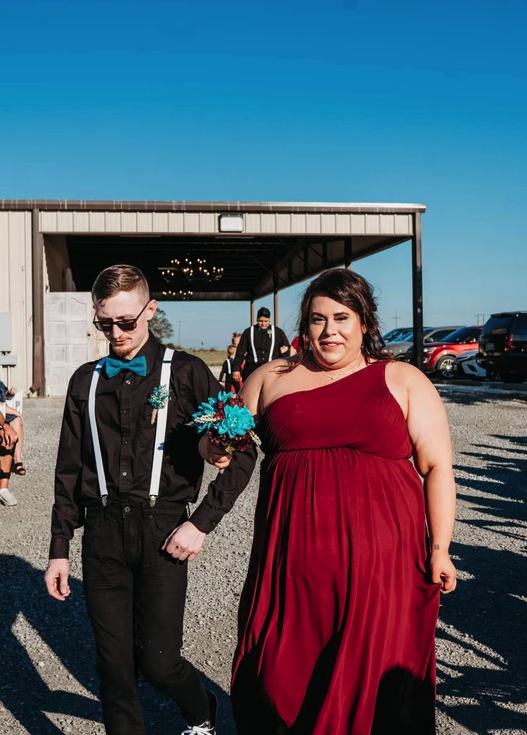 Wedding party in burgundy and teal walking from the covered pavilion under a clear Texas sky
