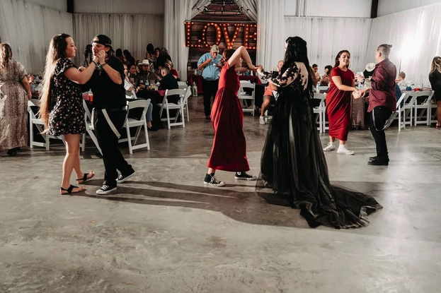 Guests partner dancing in front of the lighted LOVE marquee at the reception