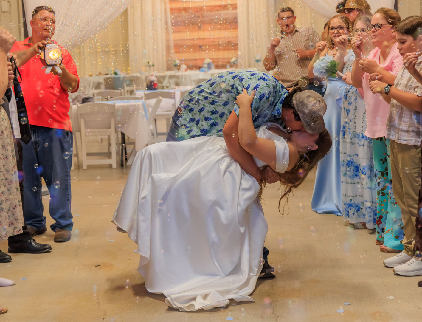 Jaelyn & Keelan's wedding at Reverie at Diamond D — the groom dips the bride for a kiss during the bubble send-off in the reception barn