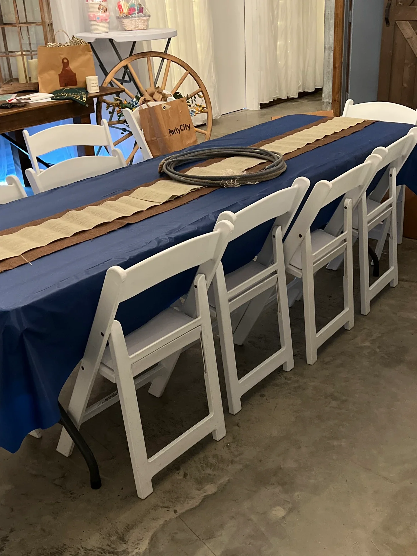 Long guest table with a navy cloth, burlap runner and coiled lariat rope centerpiece at the Love Like Bailin Therapy Farm event