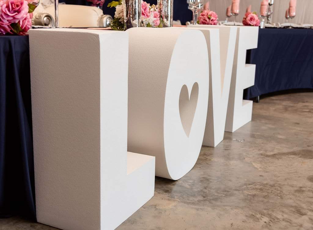 Oversized white LOVE letters displayed in front of the navy head table