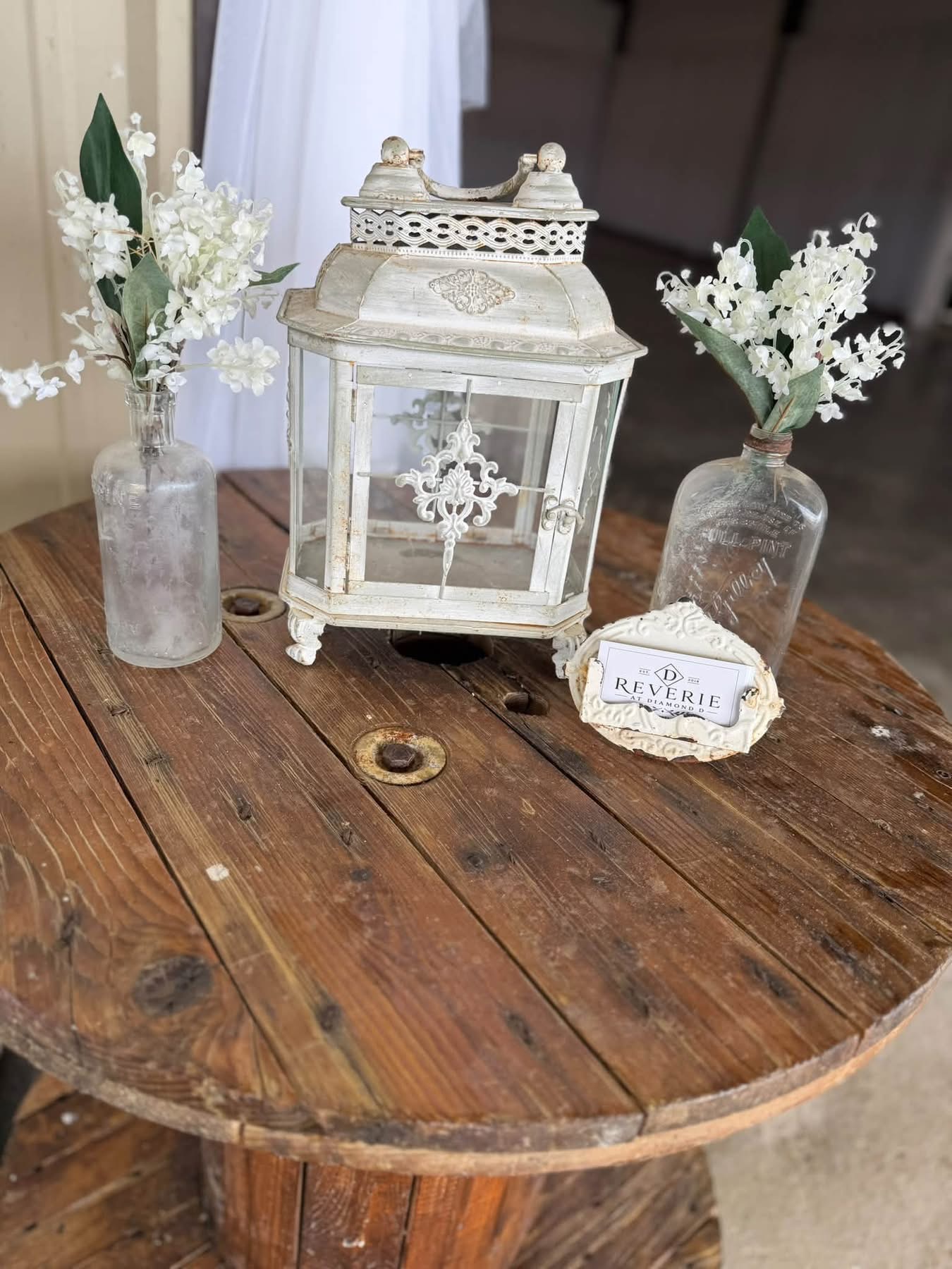 October 2026 Open House at Reverie at Diamond D wedding venue in Normangee, Texas — the Reverie at Diamond D decorative display with a vintage lantern and lily-of-the-valley stems